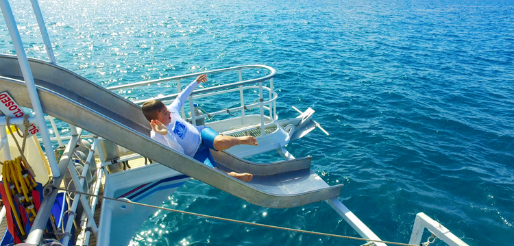 kid going down the slide into the blue hawaii ocean