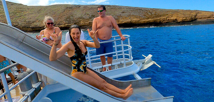 woman going down the slide into the blue hawaii ocean