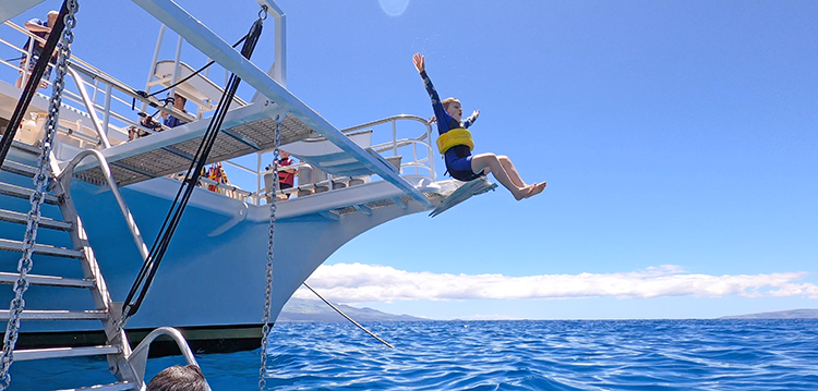 kid going down the slide into the blue hawaii ocean